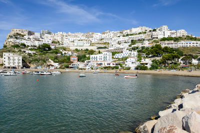 Buildings by sea against sky