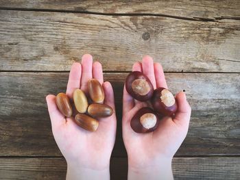 Cropped hands of person holding nuts on wooden table