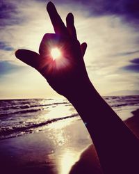 Close-up of hand holding sun over sea