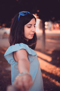 Young woman looking away while sitting outdoors