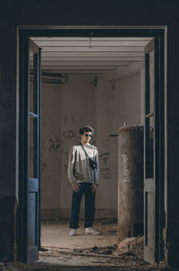 Portrait of young man standing at entrance of building