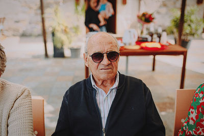 Portrait of young woman wearing sunglasses while standing in cafe