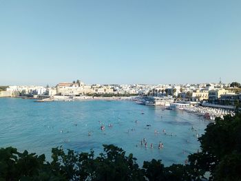 High angle view of townscape by sea against clear sky