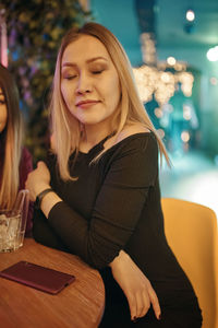 Young woman sitting on table at restaurant