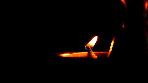 Close-up of lit candle in dark room