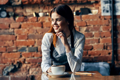 Young smiling woman looking away while sitting at restaurant