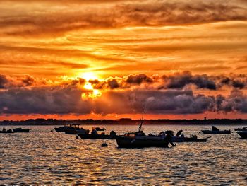 Silhouette people on shore against sky during sunset