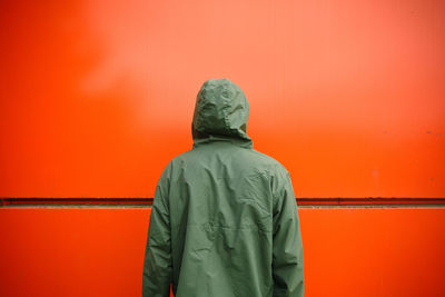 Rear view of man standing against orange wall