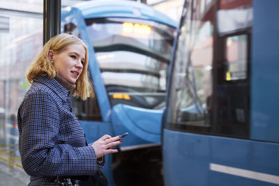 Woman using cell phone at tram stop