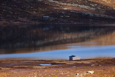 Scenic view of lake and cabin against sky