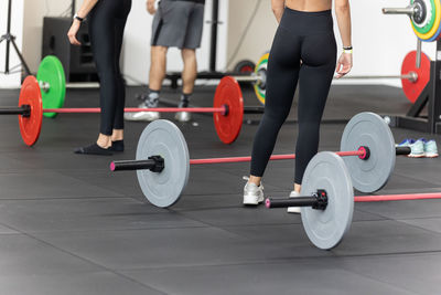 Fitness workout at gym- girls doing exercises in class with barbells.