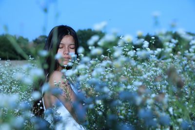 Young woman meditating amidst plants on field