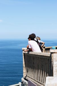Rear view of people looking at sea against clear sky