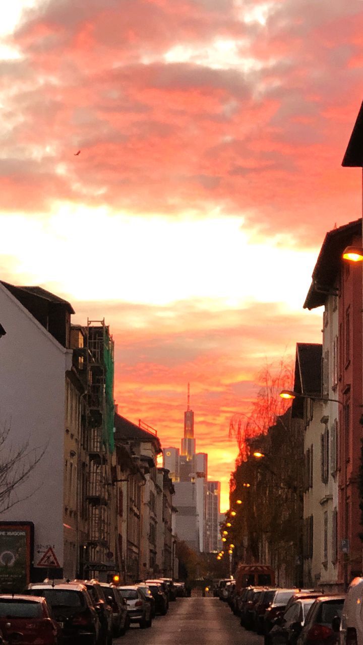 CITY STREET AMIDST BUILDINGS AGAINST SKY DURING SUNSET