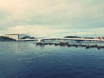 Boats in harbor against cloudy sky