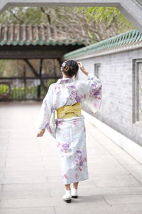 Rear view of woman wearing kimono while walking by house