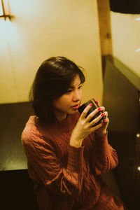 Thoughtful woman having drink at home