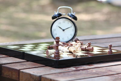 Close-up of clock with chess board on table