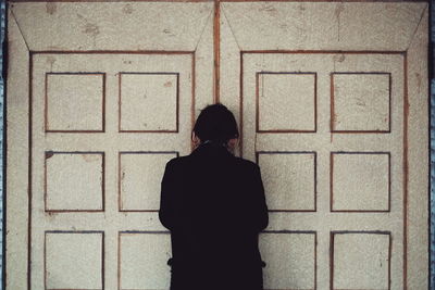 Rear view of a woman standing against wall