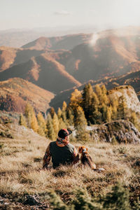 Rear view of man sitting on mountain