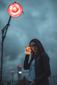 Woman holding umbrella while standing against sky
