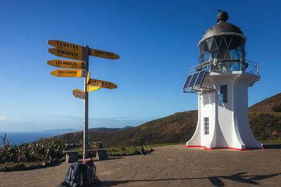 Road sign by street against clear blue sky