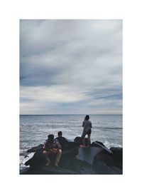 People sitting on beach against sky