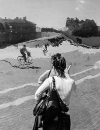 Rear view of people riding bicycle against sky