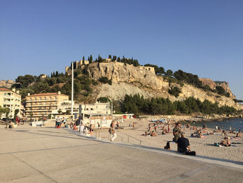 People by sea against clear sky