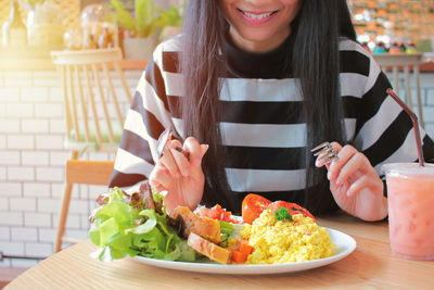 Close-up of smiling young woman with vegetables on table