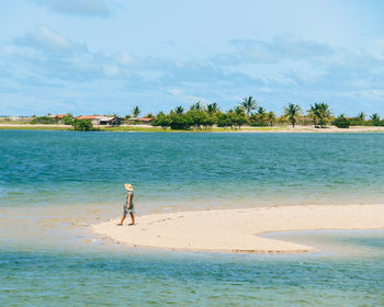 Rear view of woman walking at beach against sky