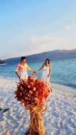 Bride and groom at beach against sky