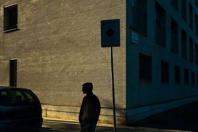 Rear view of man walking on street against building