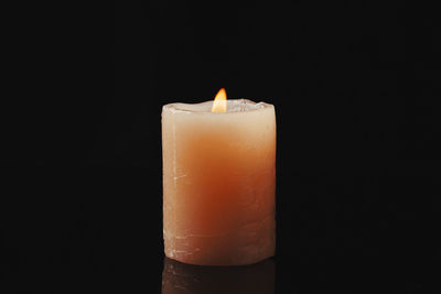 Close-up of lit candle against black background