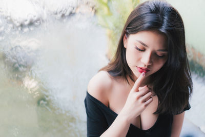 High angle view of young woman with finger on lips sitting by window