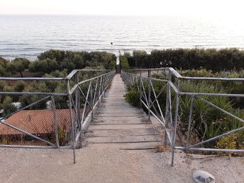 Boardwalk leading towards sea against sky