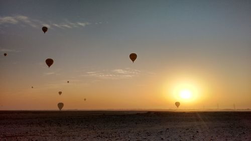 Hot air balloons flying over land during sunset