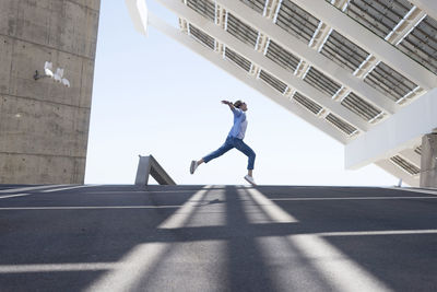 Side view of man jumping against wall