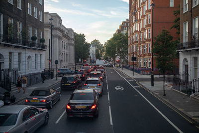 Vehicles on road amidst buildings in city against sky