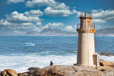 Lighthouse by sea against sky