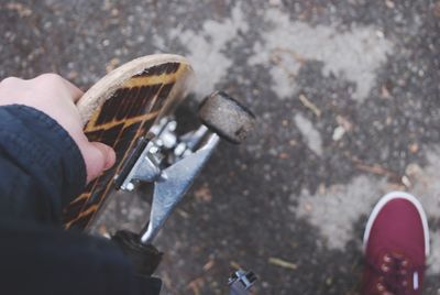 Low section of man holding skateboard on footpath