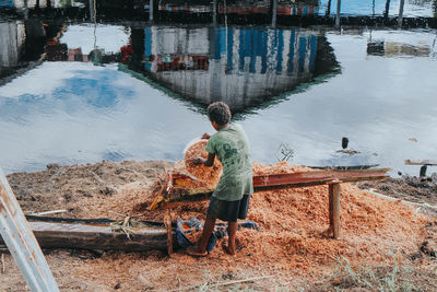 Rear view of man working at lake