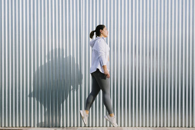 Full length side view of a man walking on metal wall