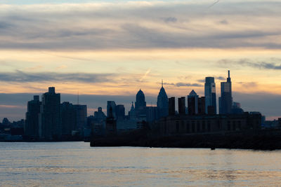 A view of the philadephia skyline over water on a dramatic blue and orange sunse