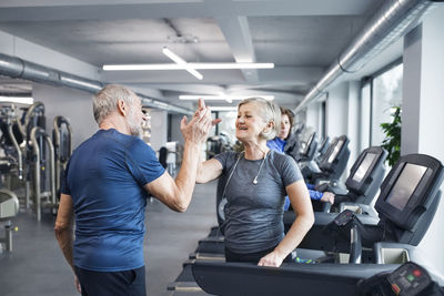 Happy senior man and woman high fiving after working out in gym