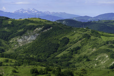 Scenic view of green landscape and mountains against sky