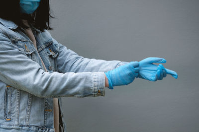 Man holding blue umbrella standing against wall