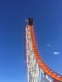 Low angle view of rollercoaster against clear blue sky