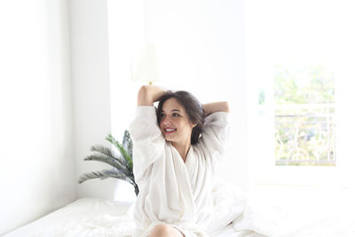 Portrait of smiling young woman lying on bed at home