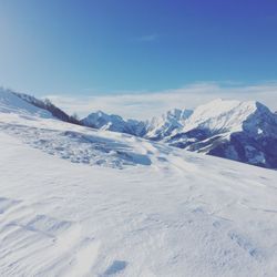 Scenic view of snowcapped mountains against blue sky